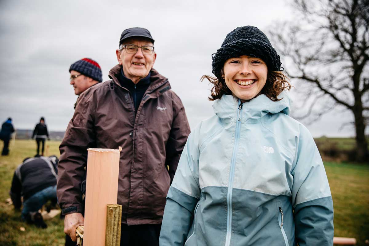 Man and woman smiling at tree planting volunteer day.