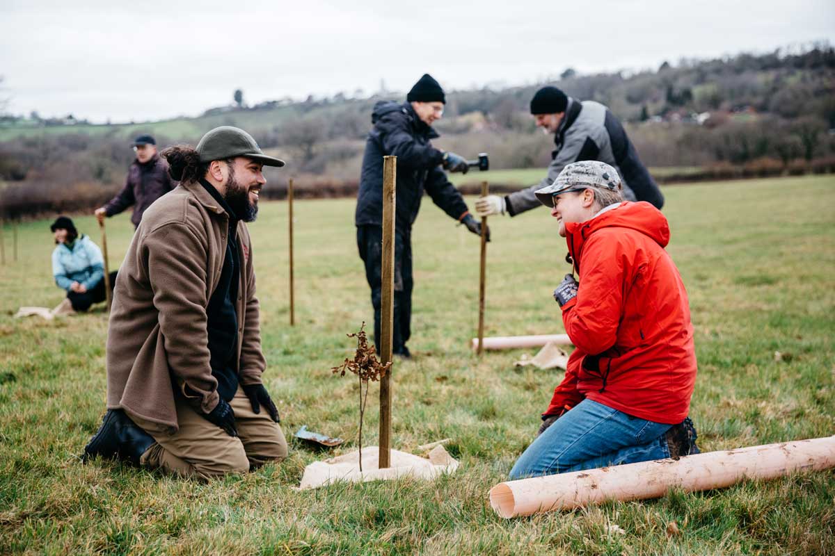 Two people talking while planting trees at a volunteer day.
